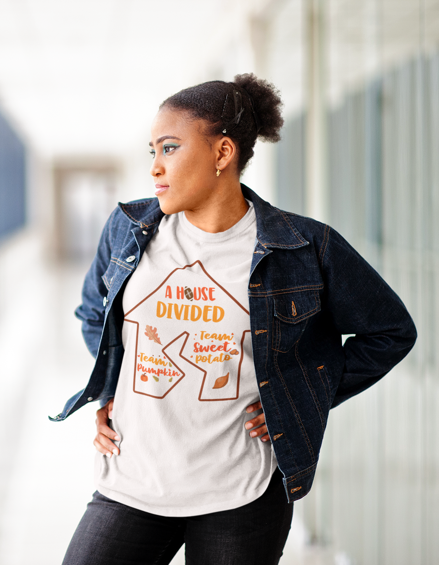 A woman wearing a A House Divided Tee by Sharp Tact Kreativ, showcasing trendy pumpkin SEO keywords.